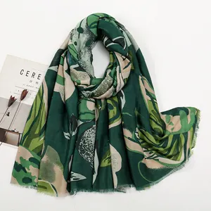Détail d'une écharpe à fleurs vert foncé avec imprimé botanique et bords effilochés