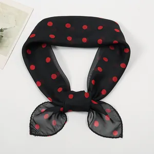 Close-up of lightweight chiffon scarf tied in a bow with red polka dot pattern