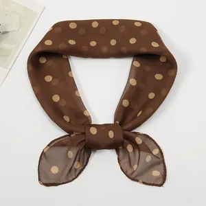 Close-up of brown chiffon scarf with yellow polka dots tied in a stylish bow knot