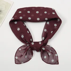 Detail of a burgundy polka dot chiffon scarf tied in a stylish decorative bow knot