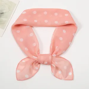 Detail of pink chiffon scarf with white polka dot pattern tied in a decorative knot