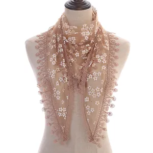 Detailed close-up of light brown floral lace triangle scarf with delicate tassel edges