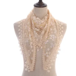 Detail showing sheer lace floral patterns and scalloped fringe on a beige triangle scarf