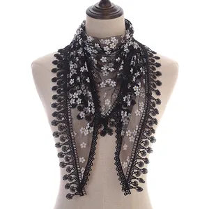 Detail of floral lace triangle scarf with black mesh fabric and delicate fringe trim