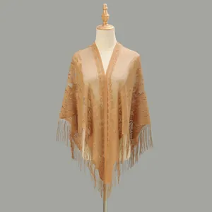 Dettaglio del motivo in pizzo vintage e lunghe frange su uno scialle color cammello