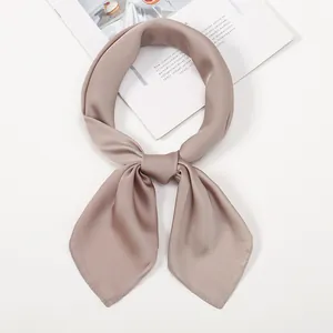 Detailed close-up of champagne silk-like scarf with satin finish and elegant knot detail