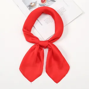 Detailed close-up of a vibrant red silk scarf tied in a knot on a white studio background