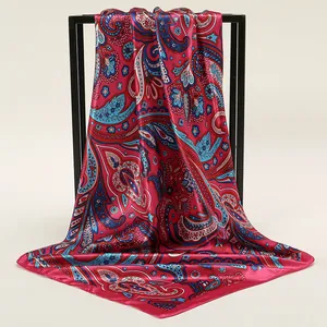 Detail of fuchsia square silk scarf with paisley patterns hanging on a black metal rack