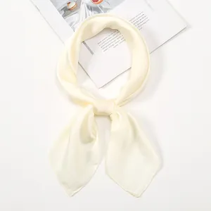 Detail of elegant cream satin square scarf tied in a silk necktie knot on a desk