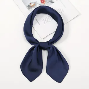 Detail of navy blue faux silk scarf tied in a neat knot on white background