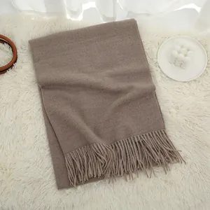 Detailed flat lay of a thick dark camel cashmere scarf featuring classic fringe edges