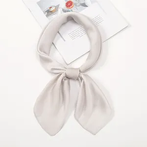 Elegant champagne satin silk neckerchief tied in a knot on minimalist magazine