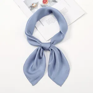 Detail of light blue satin neck scarf tied in a bow on a stylish magazine backdrop