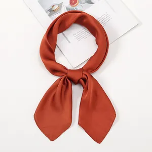 Detail of silk satin neck scarf tied in a bow showing smooth brick red texture
