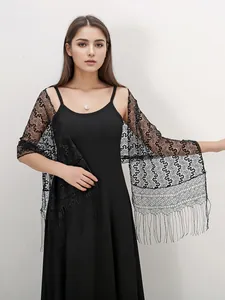 Close-up of black lace shawl with intricate hollow embroidery and tassel fringe details