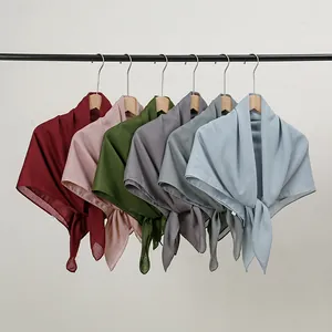 Detail view of multicolored cotton-linen scarves displayed on hangers in Morandi tones