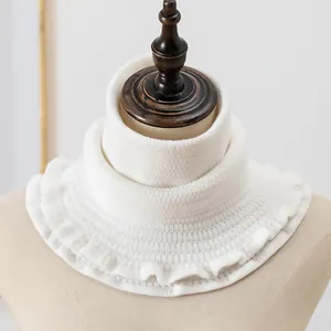 Detail of white knitted neck warmer with waffle texture and elegant scalloped edge