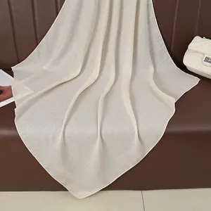 Detailed texture of beige cotton linen scarf hanging on sofa showing premium fabric weave