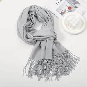 Close-up of light gray scarf with soft cashmere texture and fine tassel fringe details