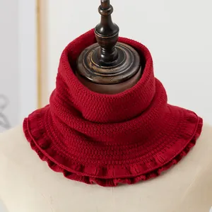 Detail of dark red knitted neck warmer with elastic ribbed texture on a wooden hanger