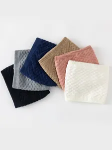 Detail of six colorful knitted neck warmers with textured square patterns and ribbed edges