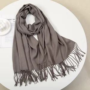 Detailed view of the soft knitted texture and woven tassels of this taupe winter scarf