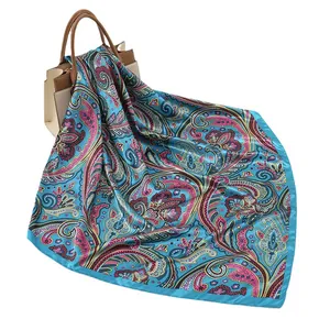 Blue paisley printed silk square scarf styled on a luxury handbag for a chic fashion look