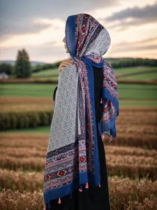 Detail of bohemian scarf with navy geometric patterns and pink tassels in sunset light