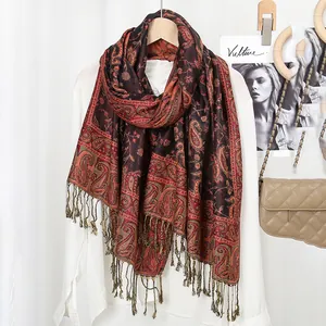 Close-up of ethnic paisley pattern and fringe tassels on a red and black scarf shawl