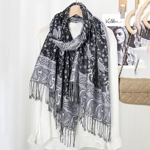 Detail of classic paisley pattern print and elegant fringe edges on a monochrome scarf