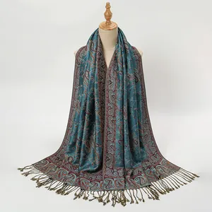Detail of elegant ethnic paisley print scarf with fringe tassels on studio model stand