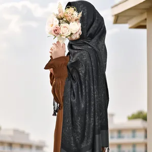 Écharpe longue noire à motif paisley jacquard avec franges portée dans un cadre élégant