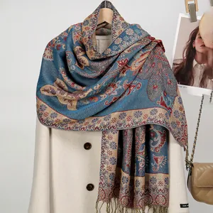 Nahaufnahme des blauen Paisley-Jacquard-Schals mit Quasten auf einem weißen Wintermantel
