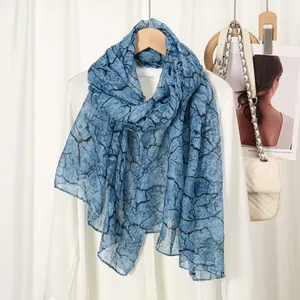 Detail of blue branch print scarf on white shirt showing its lightweight sheer fabric texture