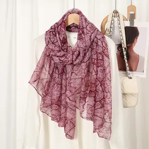 Detail shot of sheer red marble print scarf paired with white shirt on elegant backdrop