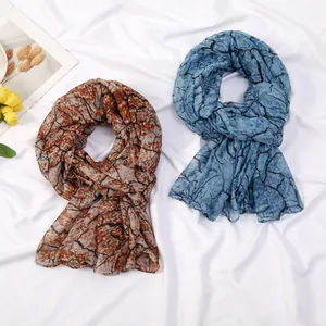 Detail of branch pattern scarves in brown and blue with lightweight soft texture