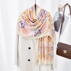 Floral print voile scarf with orange and purple patterns styled on a white coat