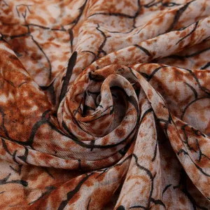 Close-up of caramel and white branch print scarf with fine mesh texture and soft drapes