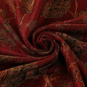 Dettaglio dello scialle etnico che mostra ricami dorati su tessuto rosso scuro