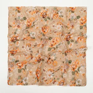 Détail d'une écharpe élégante à imprimé floral beige avec des fleurs orange sur tissu fin