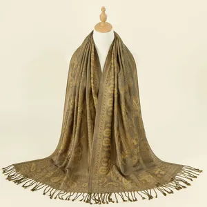 Dettaglio della sciarpa jacquard paisley bronzo con nappe decorative su un manichino