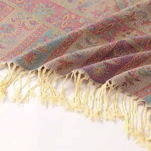 Detailed close-up of ethnic paisley jacquard fabric and woven fringe tassels on the shawl
