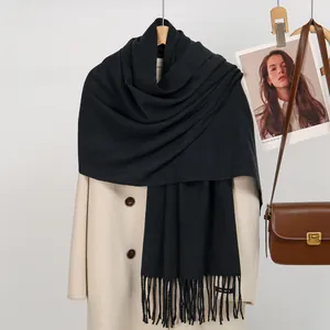 Detail of solid black faux cashmere scarf with tassels and Hand Made woven label