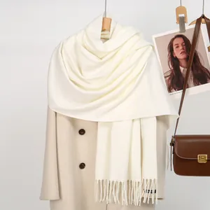 Detail of cream waffle knit scarf with tassels over a warm wool coat