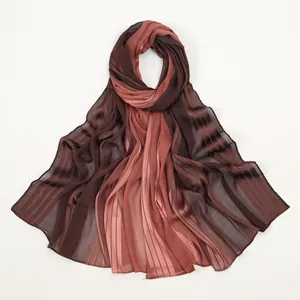 Détail d'une écharpe en satin plissé avec dégradé élégant du brun au rose poudré
