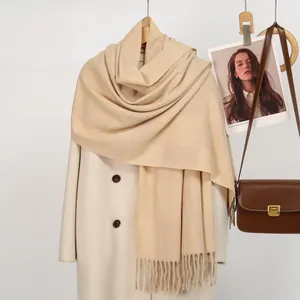 Detail of cream cashmere-feel scarf with grid texture and fringe on wool coat