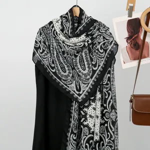Detailed view of paisley and polka dot patterns on a soft black and white beach scarf