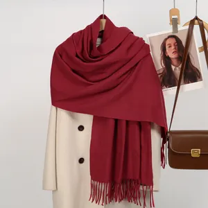 Close-up of dark burgundy winter scarf texture with fringe details and woven patterns