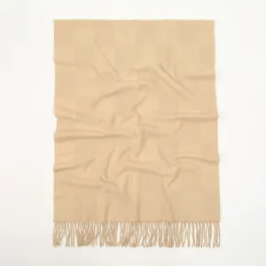 Macro detail of beige waffle weave cashmere-like scarf with fringe edges and soft texture