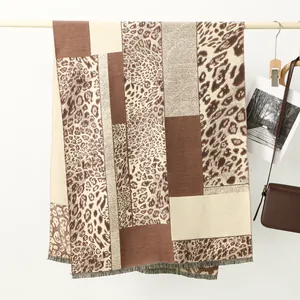 Close-up of leopard print and geometric color block scarf with delicate tassel fringe